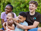 Quatre enfants, dont une fille portant un t-shirt rayé, rient en jouant dehors.