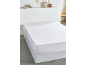 Drap-housse blanc sur matelas avec tête de lit blanche et décorations.