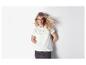 Un mannequin porte un t-shirt blanc à détails ajourés et une jupe foncée.