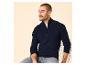 Homme en pull bleu marine à col zippé et jean, assis sur une chaise.