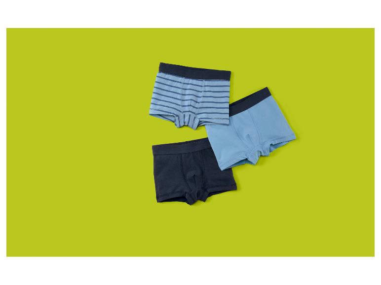 Trois slips boxers pour garçons en bleu et bleu marine, un rayé, sur fond vert lime.