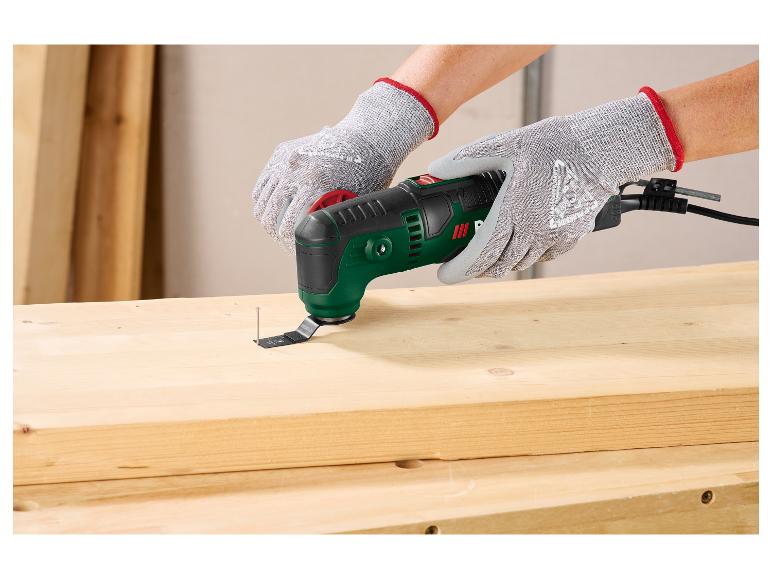 Personne gantée utilisant un outil multifonction pour retirer un clou d'une planche en bois.