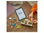 Enfant construisant un magasin pour chiens LEGO Friends avec guide numérique sur tablette.