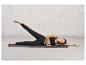 Une femme en leggings noirs et soutien-gorge de sport sur un tapis de yoga à imprimé léopard.
