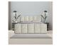 Chambre moderne avec lit double rembourré crème, tables de chevet foncées et tapis gris.
