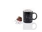 Une tasse noire avec des constellations, des barres chocolatées et des vermicelles en forme d'étoiles.