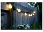 Guirlande lumineuse avec ampoules à filament, installée sur une clôture en bois.