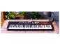 Un clavier Yamaha PSR-E363 noir sur une table en bois.
