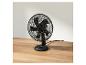 Ventilateur de bureau noir sur table en bois.
