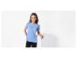 Une femme portant un t-shirt bleu clair et un pantalon noir s'appuie contre un bloc blanc.