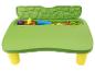 Table d'activités verte pour enfants avec pieds jaunes, remplie de jouets de sable colorés.