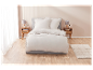 Draps beiges clairs avec volants sur un lit gris.