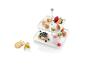 Une étagère à plusieurs niveaux avec des gâteaux, des macarons, des fruits et du yaourt.