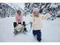 Mère et enfant dans un paysage enneigé, l'enfant tirant une luge avec la mère.