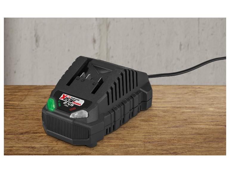 Chargeur de batterie noir avec lumière verte sur une table en bois.