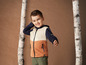 Un garçon portant une veste Hello Mini orange, beige et bleue.