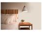 Chambre à coucher avec tête de lit en bois, literie blanche, oreillers et table de chevet avec lampe.