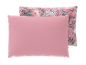 Oreiller rose avec un deuxième oreiller à motif floral derrière.