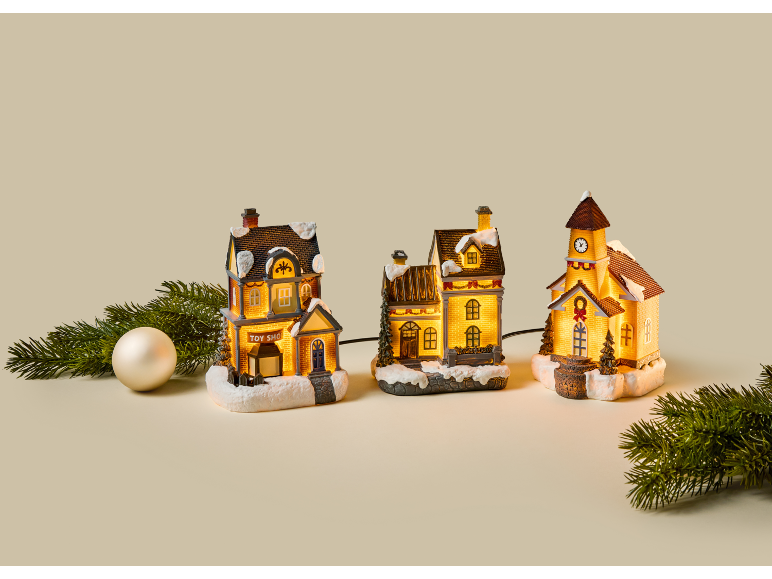 Village de Noël illuminé avec maisons, église et branches de sapin