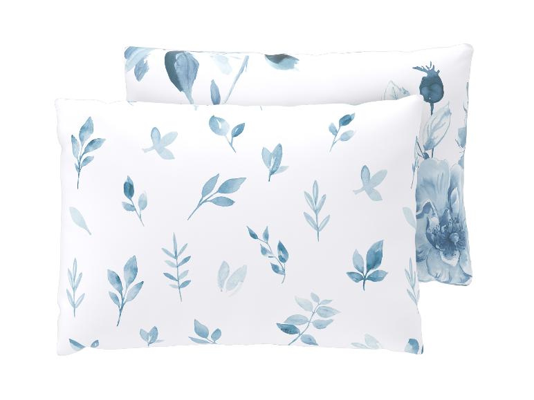 Deux oreillers blancs avec un motif de feuilles et de fleurs bleues à l'aquarelle.