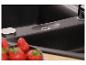 Évier de cuisine noir avec robinet et fraises au premier plan.