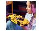 Une fille tient une voiture de sport LEGO Technic jaune sur ses genoux.