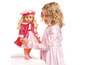Une fillette avec une robe rose joue avec une poupée en veste rose.