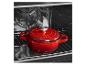 Cocotte en fonte rouge dans un four, posée sur une grille.