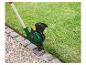 Une débroussailleuse Parkside verte avec fil pour tailler l'herbe le long d'un chemin de pierre.