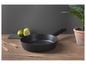 Une poêle noire sur une table en bois avec une plante dans un pot en terre cuite
