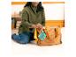 Femme assise sur le sol, rangeant un jouet Tigger dans un sac à langer marron.