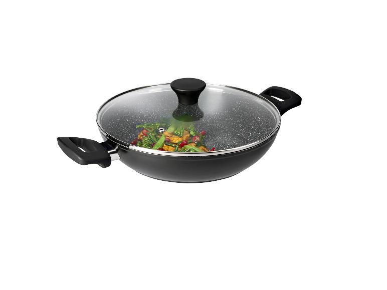 Wok noir avec couvercle en verre, rempli de légumes sautés colorés.