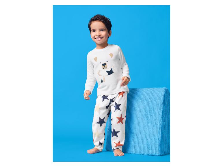 Garçon heureux en pyjama blanc avec motif d'ours et imprimé étoiles.