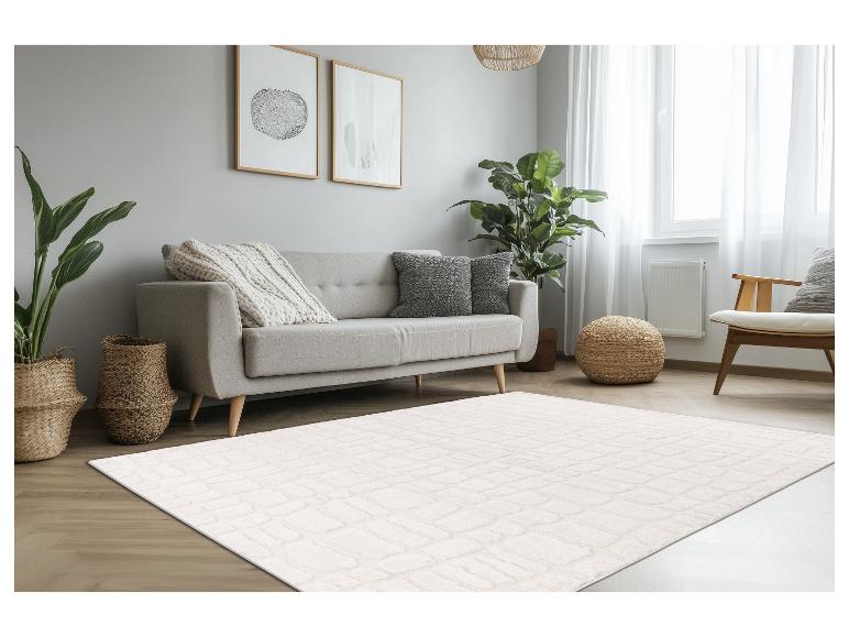 Tapis rectangulaire blanc cassé avec motif en relief dans un salon moderne et lumineux.