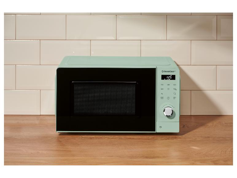Micro-ondes vert menthe avec affichage numérique et commandes dans une cuisine moderne.