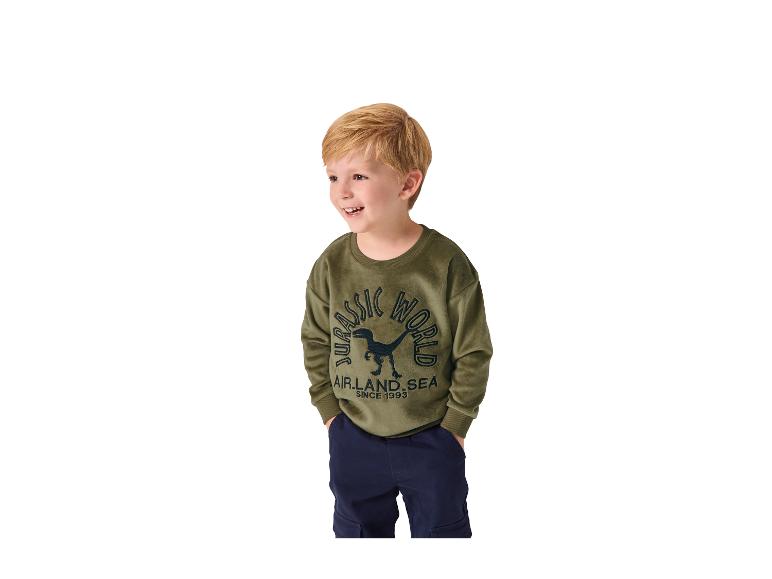 Garçon en sweat-shirt vert 'JURASSIC WORLD' et pantalon bleu foncé.