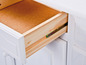 Un tiroir ouvert d'une armoire blanche avec un intérieur en bois.