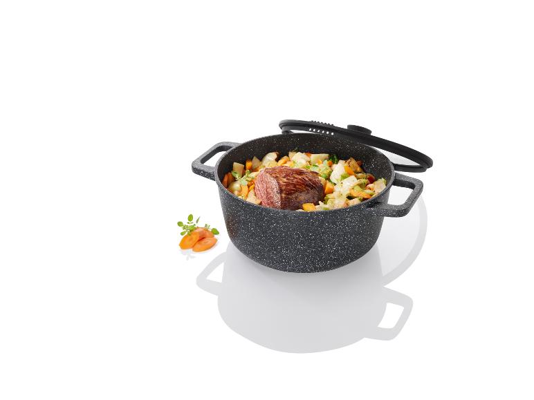 Une casserole noire avec un couvercle rempli de légumes et de viande cuits.