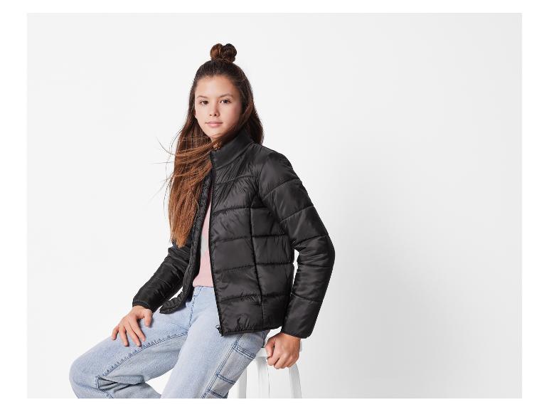 Une fille portant une veste matelassée noire et un jean clair.