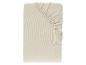 Drap-housse beige clair, plié avec le coin élastique visible.