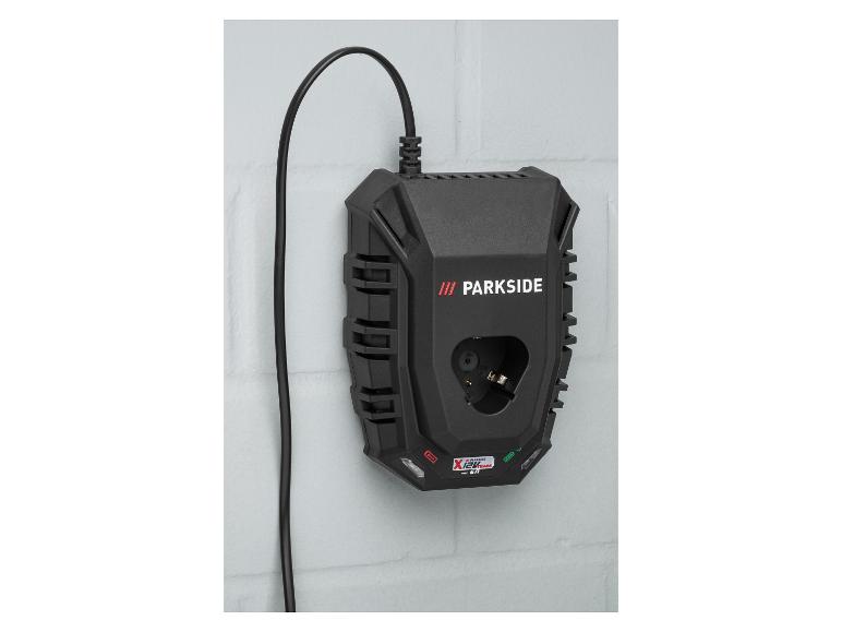 Chargeur de batterie d'outil électrique noir avec un câble, monté sur un mur de briques blanc.