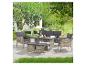 Ensemble de mobilier de jardin en rotin avec canapé, deux fauteuils, table et deux poufs sur un patio.