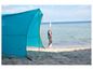 Une tente bleue Outwell sur la plage avec une femme qui marche à côté.