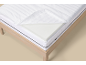 Matelas blanc avec housse amovible et surmatelas en mousse à mémoire de forme sur un cadre de lit en bois.