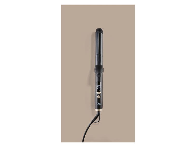 Fer à friser noir avec écran numérique et boutons de commande, posé sur un fond beige.