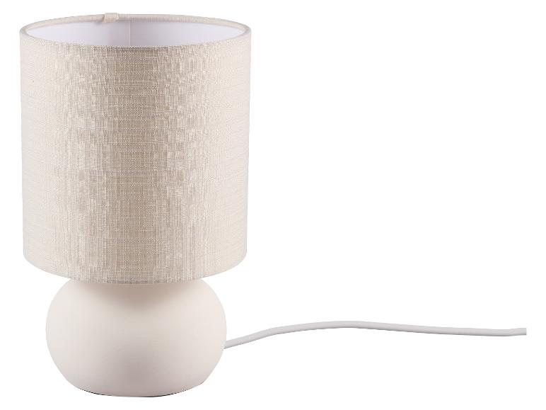 Lampe de table avec base sphérique blanche et abat-jour cylindrique en tissu beige.