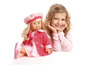Une fille portant une robe rose et une poupée avec un manteau rose.
