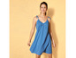 Une femme porte une robe d'été bleue avec des bretelles fines.