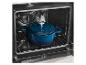 Une cocotte en fonte bleue avec couvercle à l'intérieur d'un four sur une grille métallique.