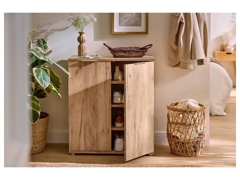 Meuble à chaussures en bois avec porte ouverte, montrant des chaussures, dans une entrée chaleureuse.